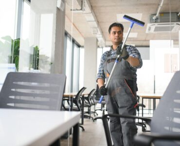 Male professional cleaning service worker cleans the windows and shop windows of a store with special equipment.