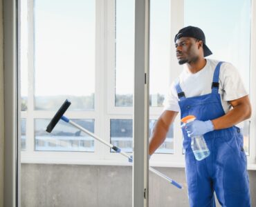 Young man cleaning window in office.