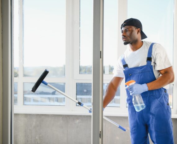 Young man cleaning window in office.